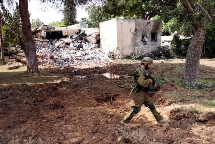 Bodies of residents and militants lie in the grounds of ravaged Israeli kibbutz